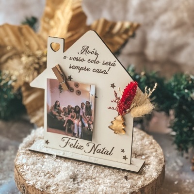 Suporte de foto em casa branca com mensagem para avós e decoração natalícia sobre base de madeira com neve