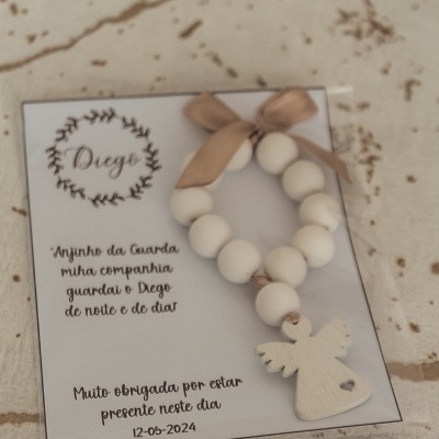 Pulseira branca com pendente de anjo e cartão com texto em português