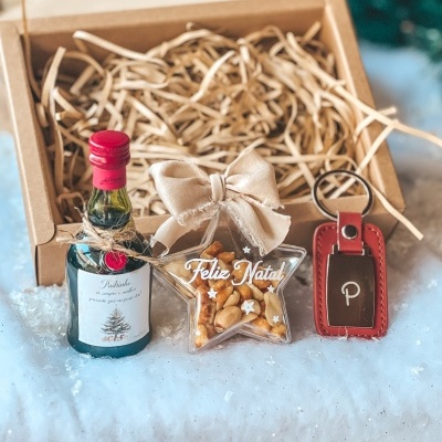 Conjunto de presente de Natal com garrafa pequena, embalagem estrela com nozes, e porta-chaves vermelho com caixa de cartão.