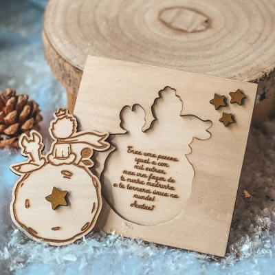 Peças em madeira do Pequeno Príncipe com estrelas douradas e fundo de neve.