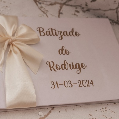 Livro de baptizado branco com laço de cetim creme e texto em dourado