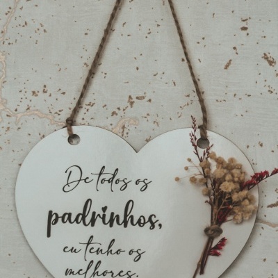Placa decorativa em forma de coração com texto e raminhos secos pendurada na parede