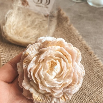 Vela esculpida em forma de flor em tons rosa claro e dourado