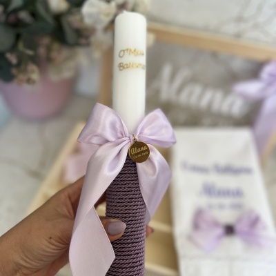 Vela decorada com laço lilás e capa roxa texturizada na mão de uma pessoa