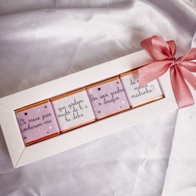 Conjunto de chocolates com texto em português em caixa branca com laço rosa