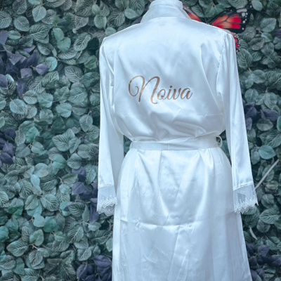 Robe branco acetinado com Noiva impresso, pendurado frente a fundo de folhas verdes