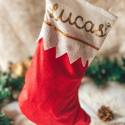 Meia vermelha de Natal com parte superior branca e nome em dourado pendurada
