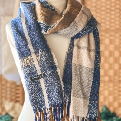 Cachecol azul, castanho e bege com franjas e etiqueta Cashmere em manequim branco