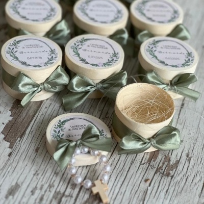 Caixas redondas creme com fita verde e pulseira de pérolas em caixa aberta sobre madeira envelhecida