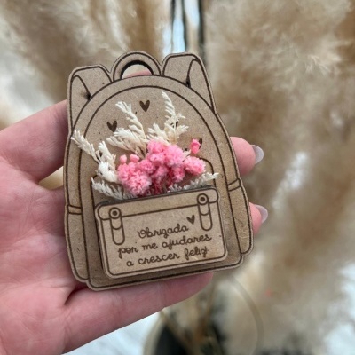 Broche em madeira com formato de mochila e flores secas cor de rosa e bege