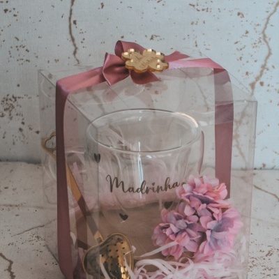 Conjunto de presente com copo de vidro, colher dourada, flores cor-de-rosa em embalagem transparente