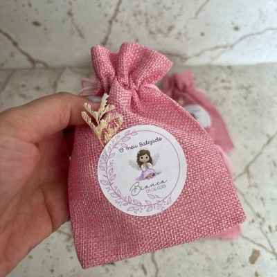 Saco de tecido rosa com etiqueta do batizado e decoração seca