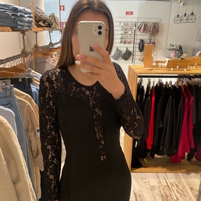 Pessoa a tirar selfie com peça preta de renda numa loja de roupa