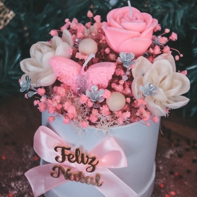 Vela decorativa com flores e laço com texto Feliz Natal