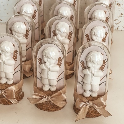 Figuras de menino em resina dentro de cúpulas de vidro com base de cortiça e laço dourado