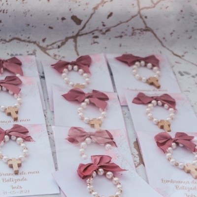 Pulseiras de pérolas com crucifixo e laço cor de rosa em cartões com texto sobre batizado