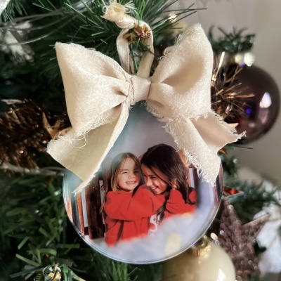 Bolinha de Natal com foto personalizada e laço de tecido na árvore de Natal