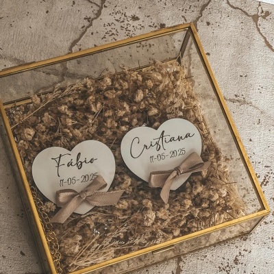 Caixa de vidro dourada com flores secas e corações decorativos de madeira com texto