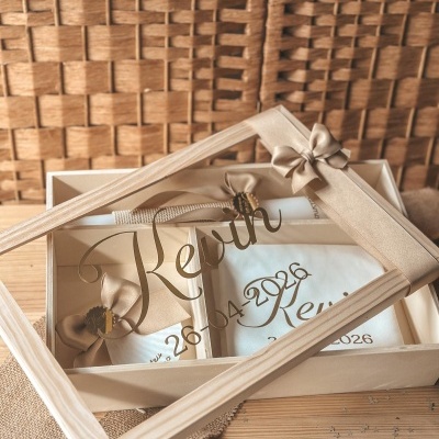 Caixa de presente em madeira clara com tampa acrílica gravada, contendo lenços brancos com laços dourados