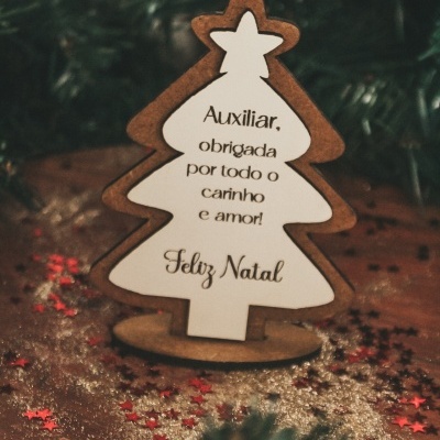 Figura de árvore de Natal em madeira com texto em português, decorada com glitter e estrelas sobre superfície de madeira