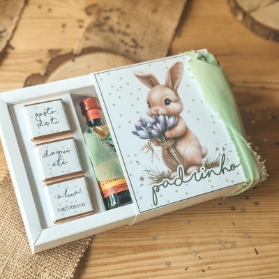 Conjunto de presente de Páscoa com mini chocolates, garrafa de licor e embalagem com coelho e texto padrinho.