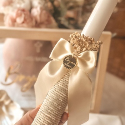 Vela branca decorada com fita, cordão, laço e flores secas com etiqueta personalizada.