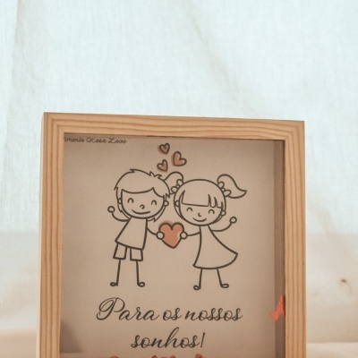 Caixa decorativa com desenho infantil de menino e menina segurando coração e texto em português.