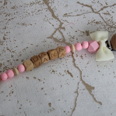 Prendedor de chucha com contas de madeira e silicone rosa e bege com nome LUANA e laço branco
