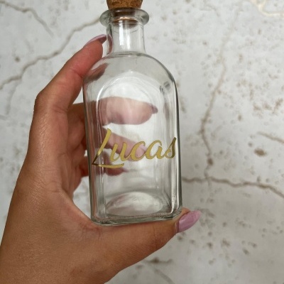 frasco de vidro transparente com tampa de cortiça e nome Lucas em dourado