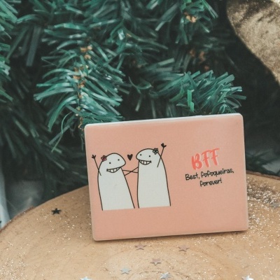 Prenda rosa com ilustração e texto BFF sobre base de madeira com decoração natalícia