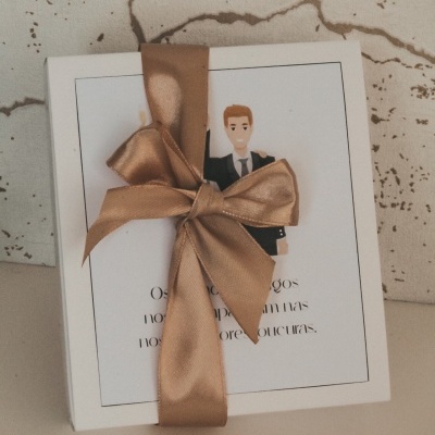 Caixa branca com fitas castanhas e ilustração de homem de fato preto