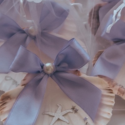 Conchas decorativas com laço lilás e etiqueta de batismo