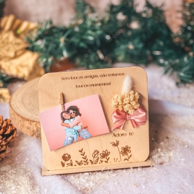 Porta-fotos em madeira clara com foto, texto e laço rosa com flores secas