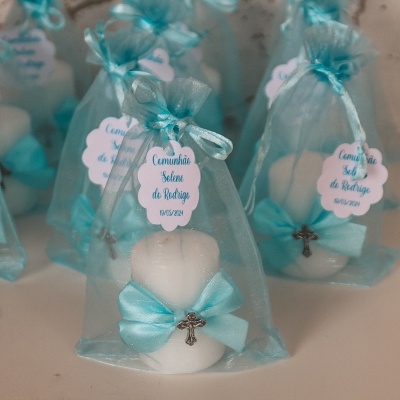 Velas decorativas em forma de coração com fitas azuis e cruzes dentro de saquinhos de organza azuis