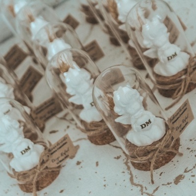 Esculturas de anjos brancos em abrigos de vidro com base de cortiça e etiquetas de papel