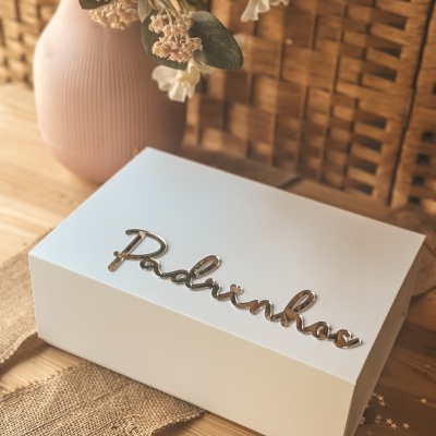 Caixa branca com texto metálico prateado Balonhos e jarra rosa com flores