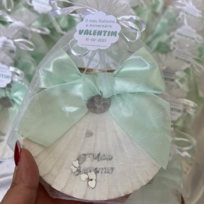 Sapatilha de bebé branca com laço verde água em saco de tule com etiqueta de batismo.