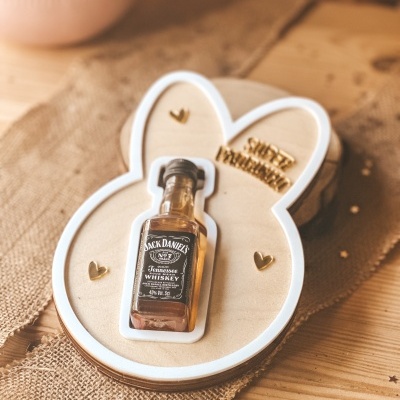 Miniatura garrafa whisky Jack Daniels em suporte de madeira em forma de coelho.