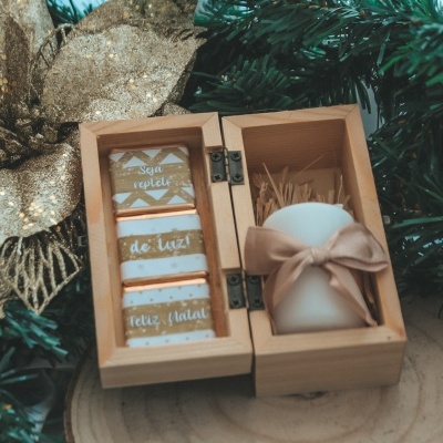 Caixa de madeira aberta com vela branca e cartões de texto em decoração natalícia