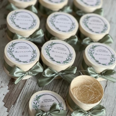 Pequenos frascos com tampa decorada e laço verde sobre superfície de madeira