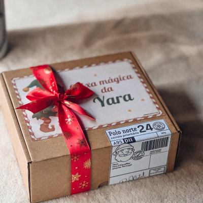 Caixa de presente castanha com fita vermelha e etiqueta personalizada.