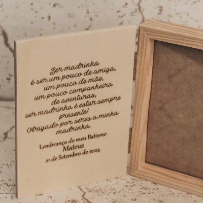 Placa de madeira gravada com mensagem para madrinha ao lado de moldura de madeira vazia
