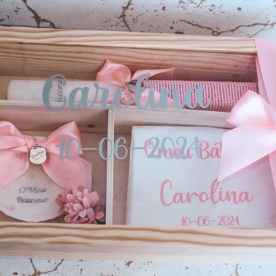 Caixa de madeira com itens para batizado decorados com laços cor-de-rosa