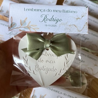 Lembrança de batismo com coração branco, laço verde e cartão personalizado com nome e data.