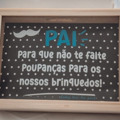Quadro decorativo com moldura de madeira e texto em português sobre fundo preto com bolinhas brancas