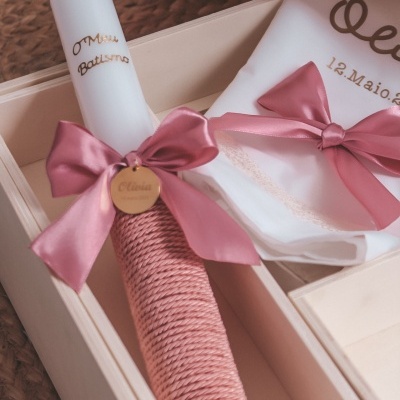 Vela e toalha decoradas com laços rosa em caixa de madeira clara