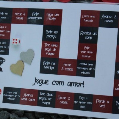 Tabuleiro de jogo com instruções em português e dado sobre pedras coloridas