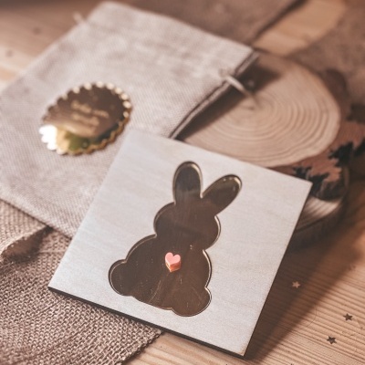 Decoração de madeira clara com silhueta de coelho e coração cor-de-rosa