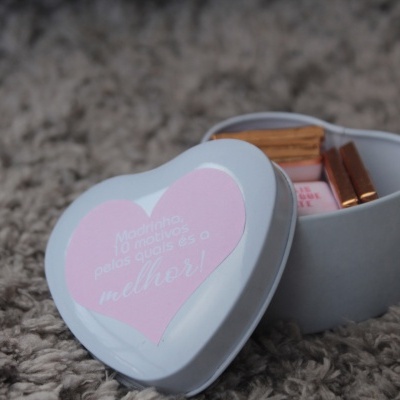 Caixa de metal em forma de coração com produtos dentro sobre tapete cinza