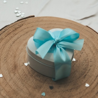 Caixa de presente branca em forma de coração com fita azul sobre tábua de madeira